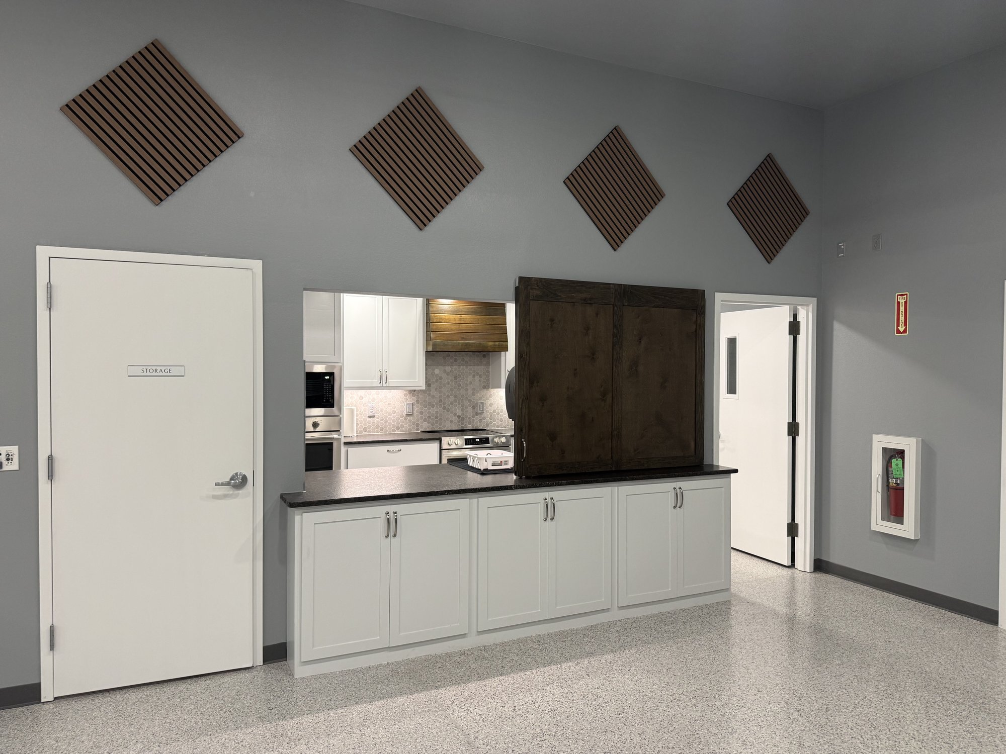 Kitchen pass-through with white cabinets and dark counter in the Community Room