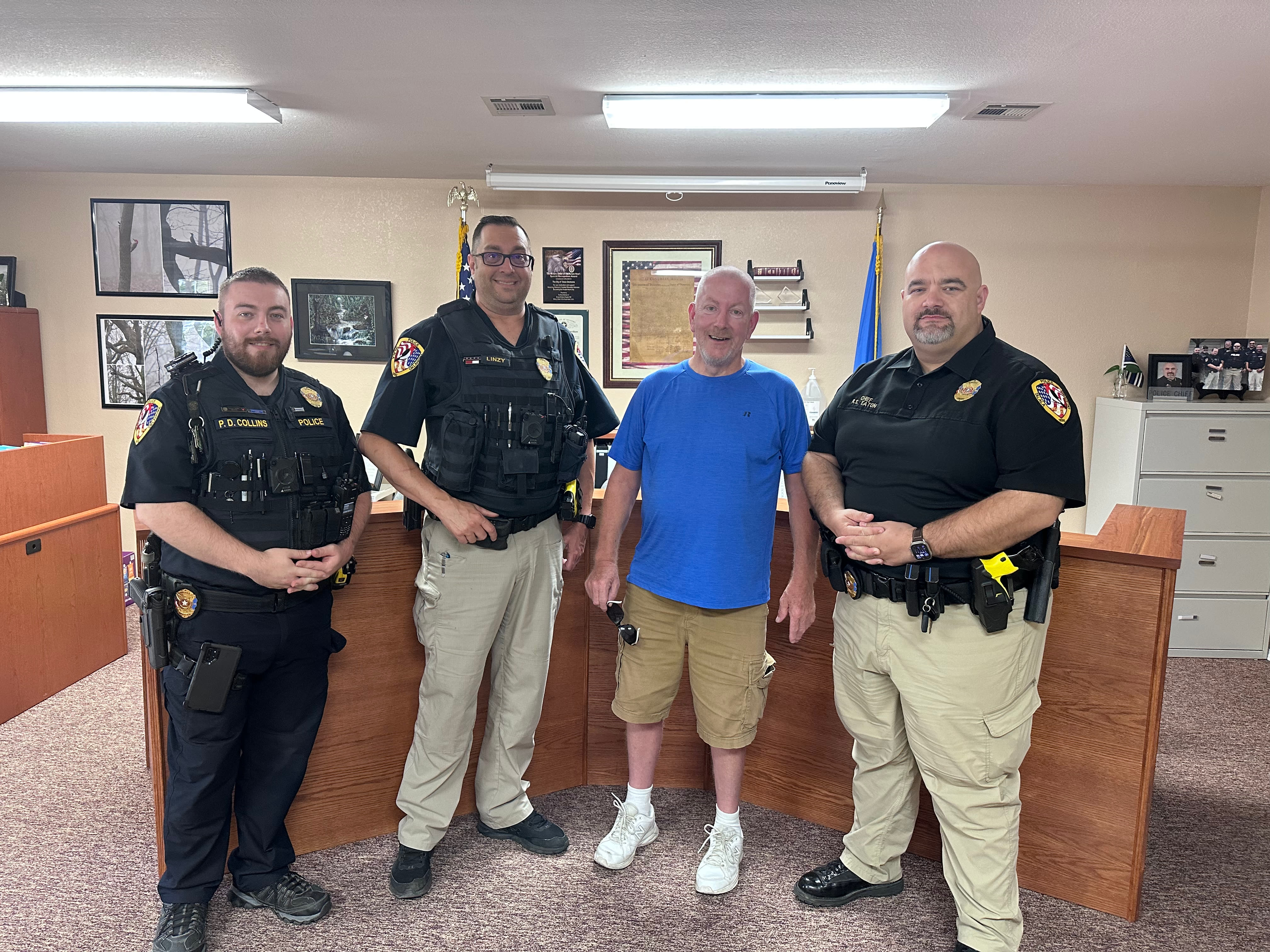 Officers Collins and Linzy and Chief Eaton with a community member at Town Hall / the Police Department lobby